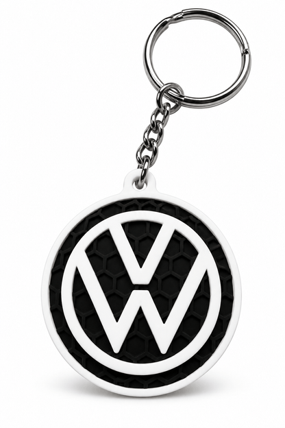 Privjesak za ključeve s bijelim Volkswagen logotipom na crnoj teksturiranoj podlozi, uz metalni lanac i prsten